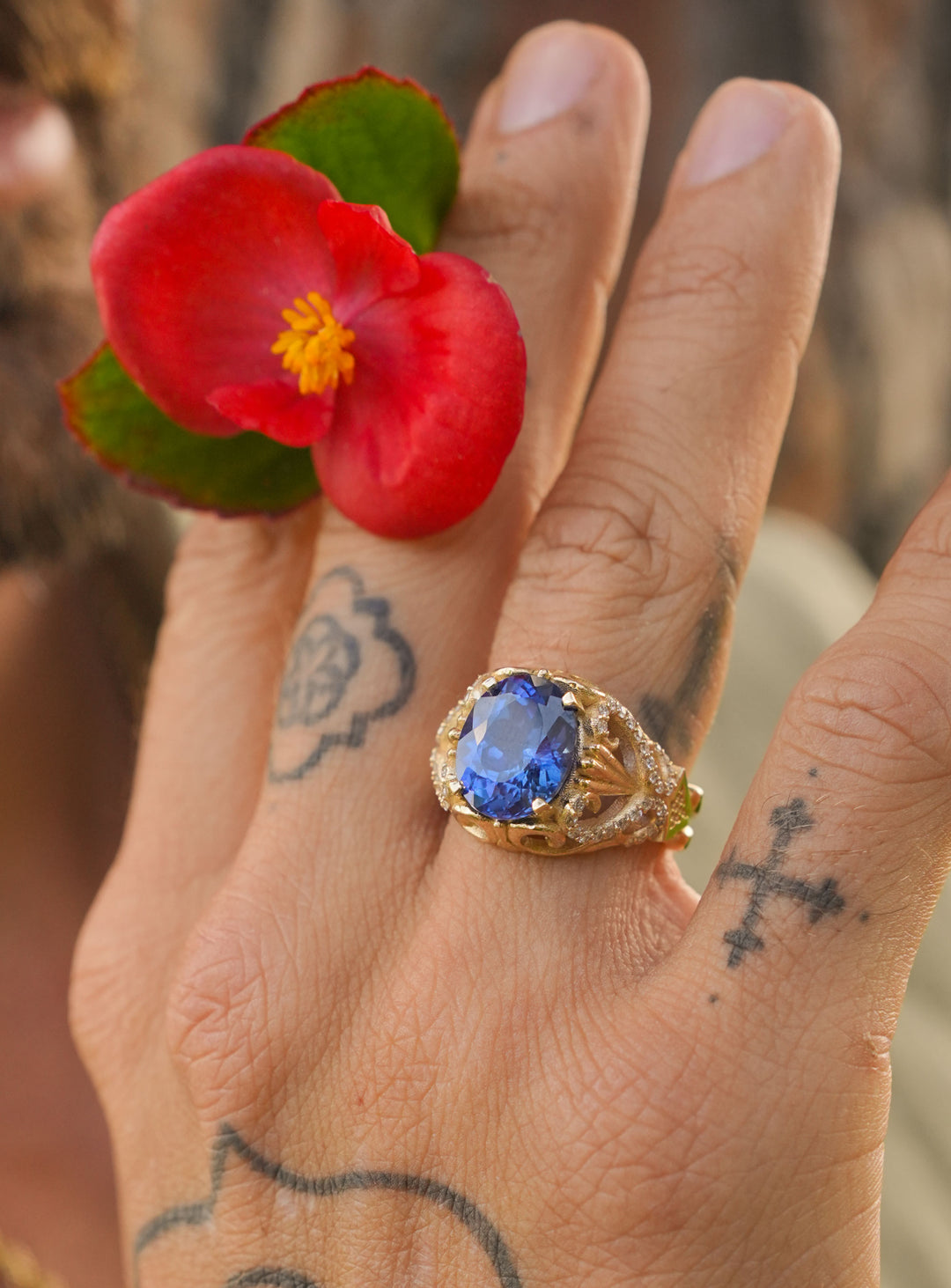 Gold ring with an oval blue sapphire center stone, intricate filigree design, and diamond accents, inspired by Mediterranean elegance.