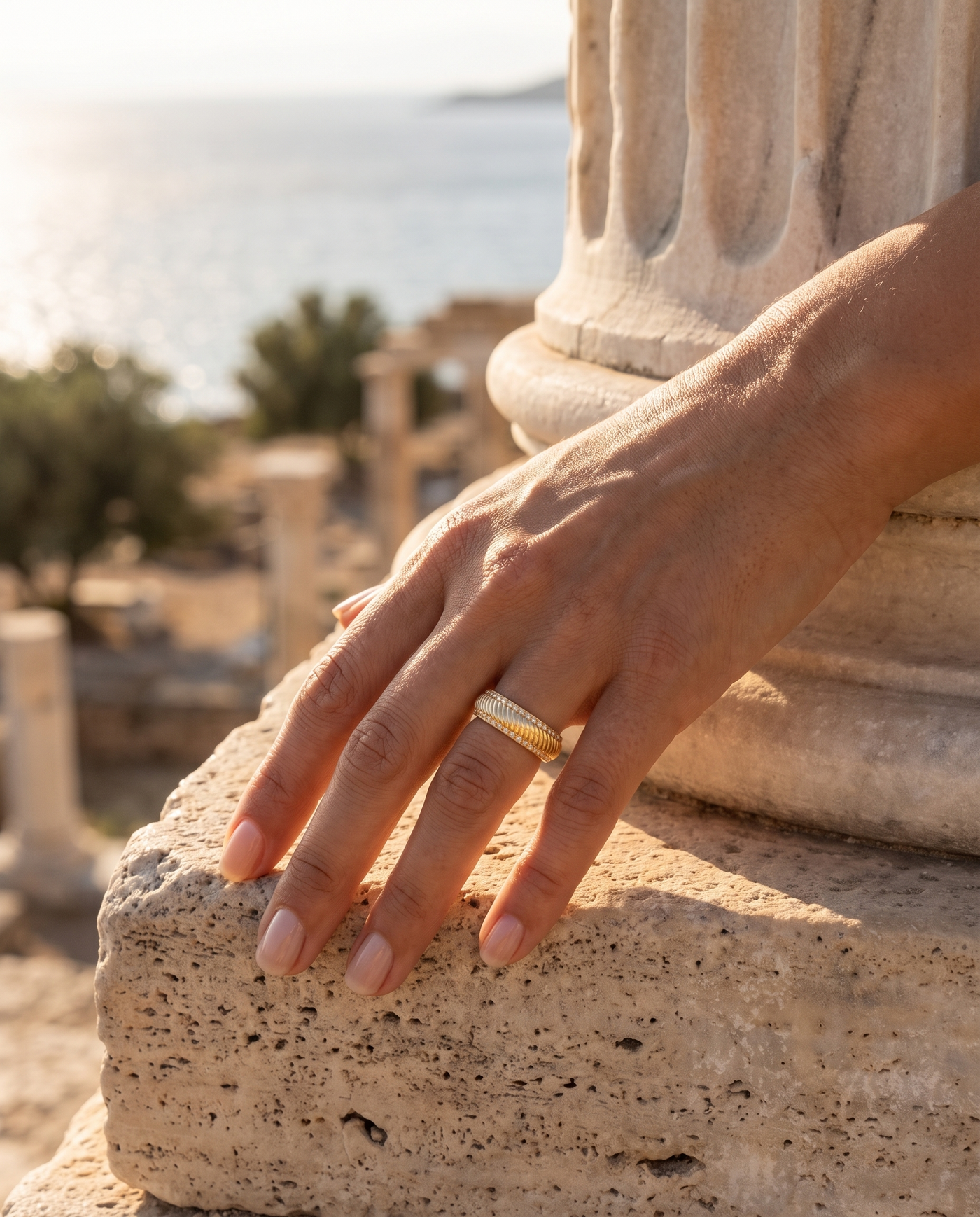 The Riviera Ring worn on a hand by an ancient column overlooking the sea