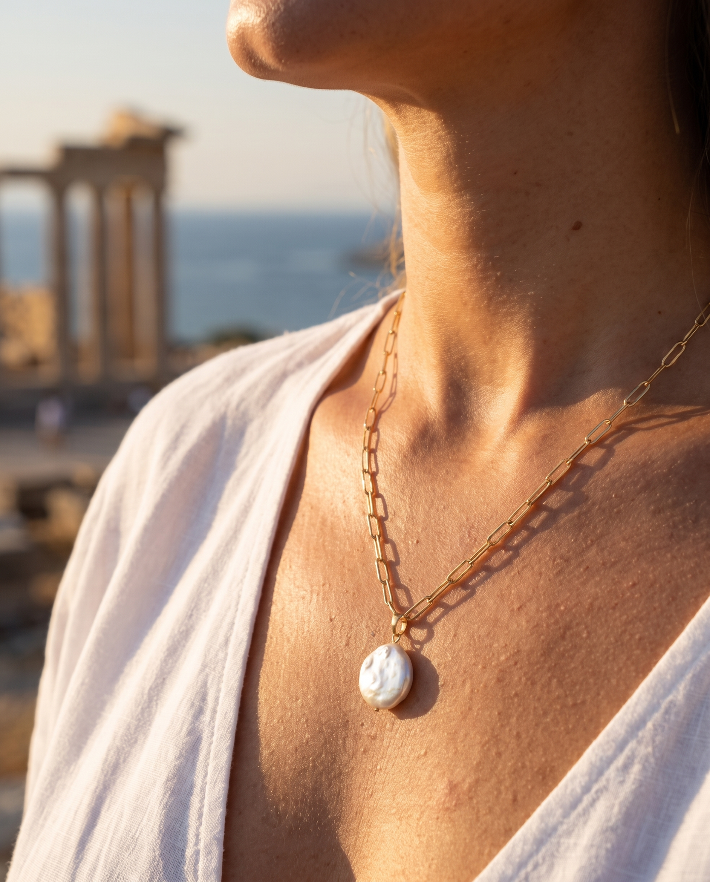 Sunlit Pearl necklace worn at the decolletage overlooking the sea