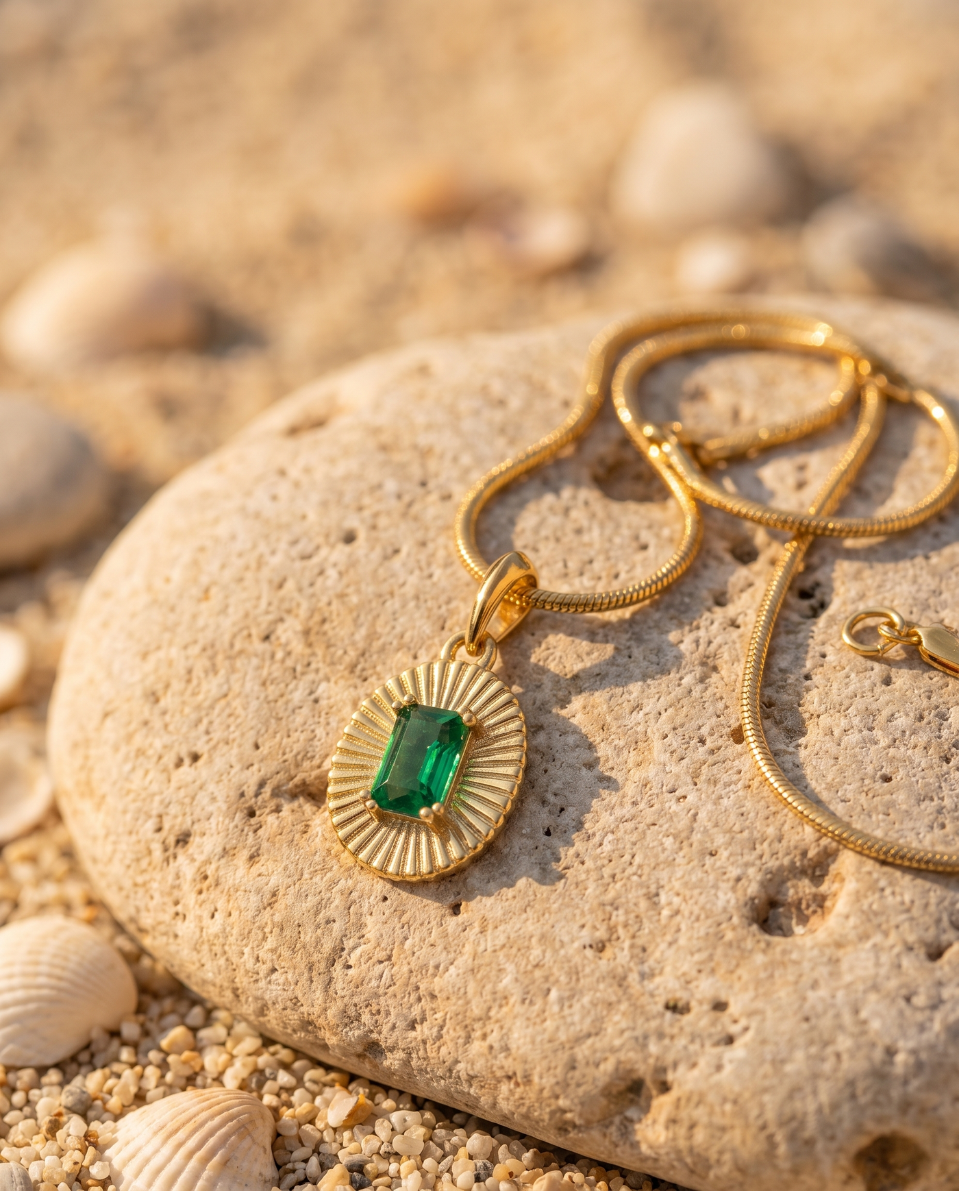 Emerald Sunburst Pendant on an Aegean beach stone at golden hour