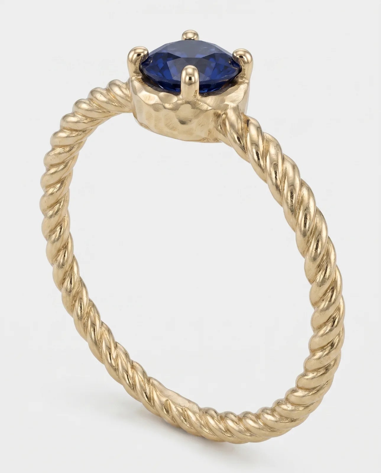 Meltemi Ring in 14k yellow gold, a round blue sapphire in a hammered bezel on a twisted rope band, standing upright on a plain white studio background.