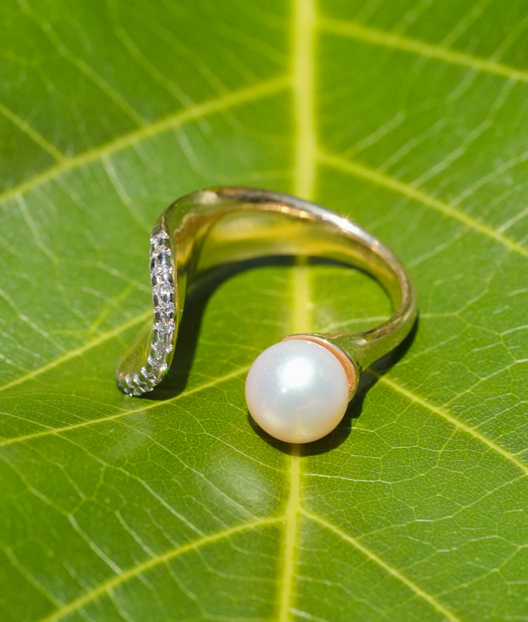 Gold open ring with a pearl and pavé diamond arc, showcasing modern elegance and timeless design