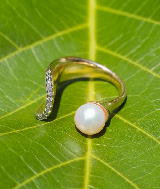 Gold open ring with a pearl and pavé diamond arc, showcasing modern elegance and timeless design